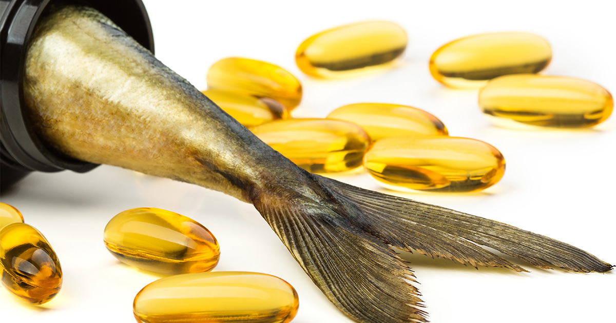 Fish tail sticking out of a supplement bottle among fish oil capsules